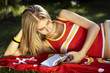 young lady in the garden reading and relaxing on the red towel