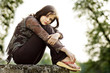 Young Woman sitting in the park, thoughtful and looking away