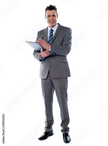 Photo: Smiling businessman writing on clipboard Smiling businessman writing on clipboard