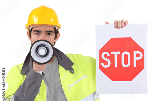 Photo: road worker holding a stop sign and talking through a megaphone road worker holding a stop sign and talking through a megaphone