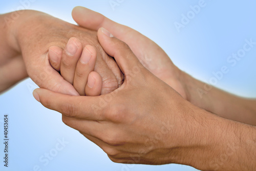 Photo: Junger Mann hält Hand einer älteren Frau- Hintergrund blau Junger Mann hält Hand einer älteren Frau- Hintergrund blau