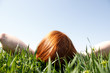 Red haired woman laying in grass looking up