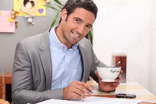 Photo: Businessman working in his kitchen with a cup of coffee Businessman working in his kitchen with a cup of coffee