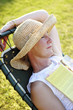 A woman in a straw hat sleeping on a rest chair.