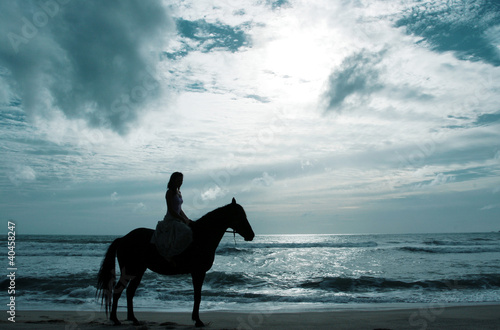 Photo: A woman horse riding on the beach. A woman horse riding on the beach.