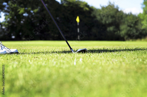 Foto: A golf club putting a golf ball into the hole. A golf club putting a golf ball into the hole.