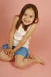 Studio shot of a girl in blue skirt sitting on the floor.