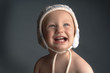 A baby with bonnet laughing while looking up.