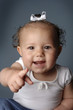 A girl with white ribbon pointing at the camera.