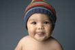 A baby with hat showing tongue at the camera.