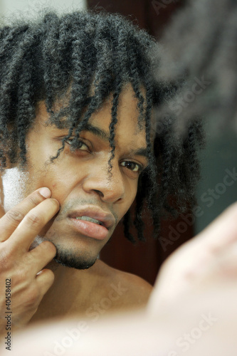 Photo: A african american man checking the cut on his face. A african american man checking the cut on his face.