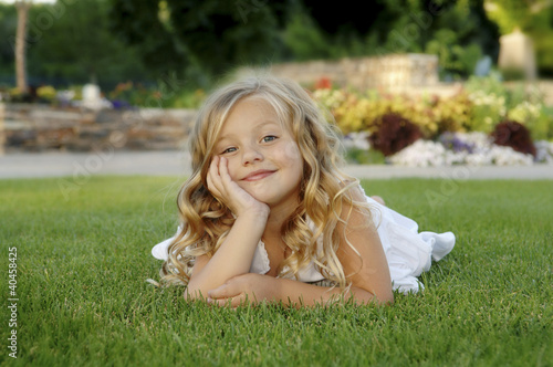 Photo: A girl in white dress lying forward on the grass. A girl in white dress lying forward on the grass.