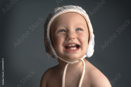 Photo: A baby with bonnet laughing while looking up. A baby with bonnet laughing while looking up.