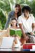 Two ladies and a african american man sharing a book.