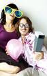 A guy using a polaroid camera to take the picture of him and his girlfriend in fun glasses.