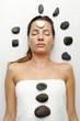 A sleeping lady with a white stone on her forehead and black stones on her body and around her head.