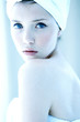 Side shot of a woman with her hair and body wrapped up in towel looking at the camera.