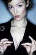 A woman pulling the collar of her jacket revealing her cleavage.