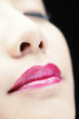 A close-up picture of a lady in bright pink lipstick closing her eyes.