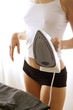 Photo: Shoulder down shot of a braless woman in white camisole and black panties ironing her clothes. Shoulder down shot of a braless woman in white camisole and black panties ironing her clothes.