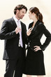 A man and woman standing face to face with each holding a handphone.