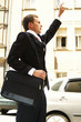Side shot of a man in business suit with a sling bag stopping a taxi.