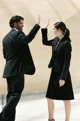 Foto: A guy giving his female colleague a high five. A guy giving his female colleague a high five.