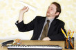 Photo: a man in business suit sitting at his desk playing with a paper plane. a man in business suit sitting at his desk playing with a paper plane.