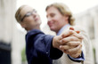 side shot of couple in office attire doing a tango dance.