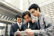 Three men in formal wear sharing a newspaper.
