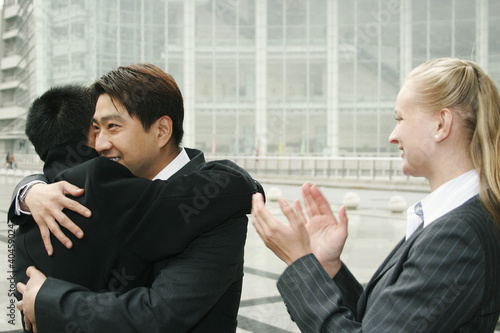 Foto: An asian man hugging his friend while a lady clapping her hands. An asian man hugging his friend while a lady clapping her hands.