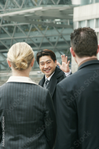Photo: An asian man waving goodbye to a man and woman. An asian man waving goodbye to a man and woman.
