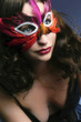 A woman in a mask wearing a low-cut dress exposing her cleavage.