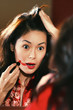 A woman in oriental bathrobe overdrawing her lipstick out of her lips.