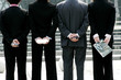 Back shot of a group of business people hiding their stuff.