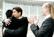 Two men hugging each other while a woman clapping her hands. 