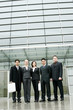 Photo: A group of business people standing in front of their office building. A group of business people standing in front of their office building.