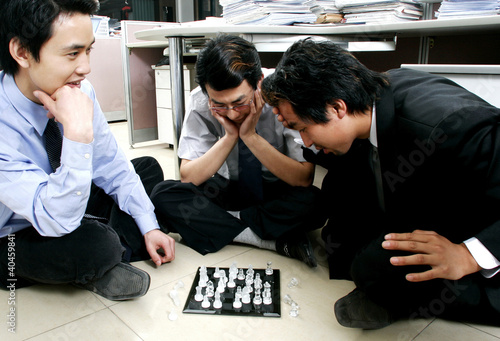 Foto: A group of men playing chess in the office. A group of men playing chess in the office.