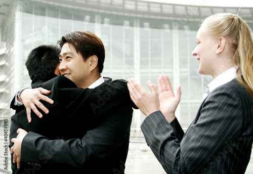 Photo: Two men hugging each other while a woman clapping her hands. Two men hugging each other while a woman clapping her hands.
