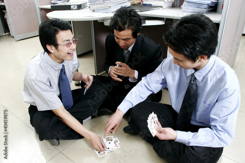 Foto: A group of men playing cards in the office. A group of men playing cards in the office.