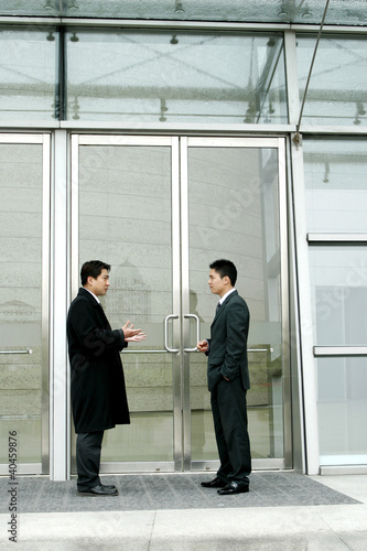 Photo: Two men in business suits talking. Two men in business suits talking.