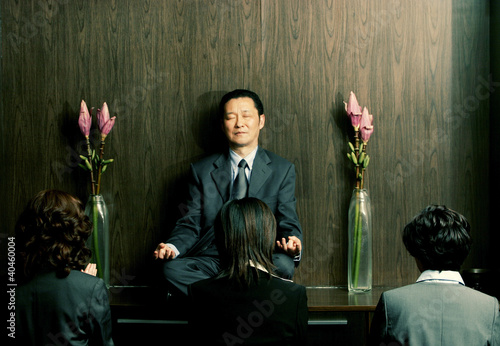 Photo: Three women praying in front of a meditating man. Three women praying in front of a meditating man.