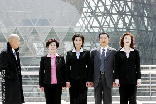 Photo: A bald man watching a group of business people standing in a row. A bald man watching a group of business people standing in a row.