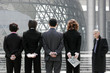 Back shot of business man and women standing in a row hiding their stuff. 