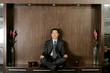 Man in business suit sitting on the shelf meditating. 