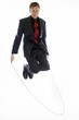 Man in business suit playing with skipping rope. 