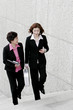 Two business women chatting while walking up the stairs. 