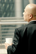 Photo: Back shot of a bald man in business suit holding a cup. Back shot of a bald man in business suit holding a cup.