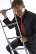 Businessman looking scared climbing up the ladder. 