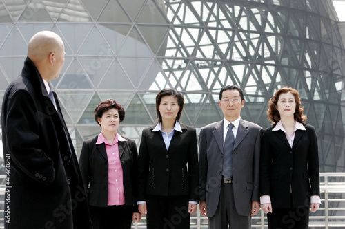 Photo: A bald man watching his employees standing at attention. A bald man watching his employees standing at attention.
